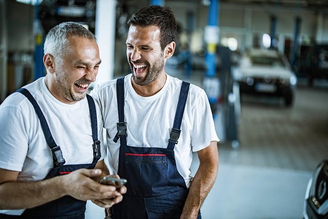 Zwei lachende Mitarbeiter einer Autowerkstatt